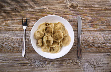 plate with homemade meat dumplings sprinkled with black ground pepper stands on a wooden tableの写真素材