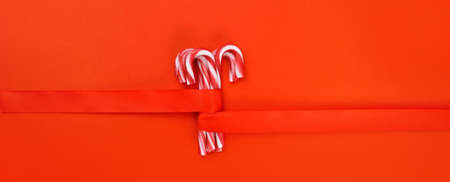 caramel canes with red ribbon on red background. High quality photoの写真素材