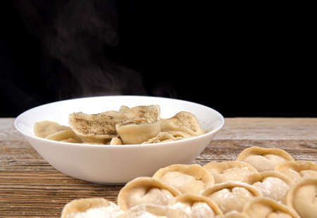 plate of homemade dumplings, and not boiled standing on the board. selective focus .の写真素材