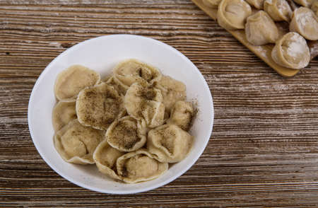 plate of homemade dumplings, and not boiled standing on the board. selective focus .の写真素材