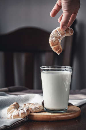 child hand holds cookie next to glass of milk. selective focusの写真素材