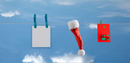 rope on which a plastic card, Santa hat and postcard hang against the blue sky. selective focusの写真素材
