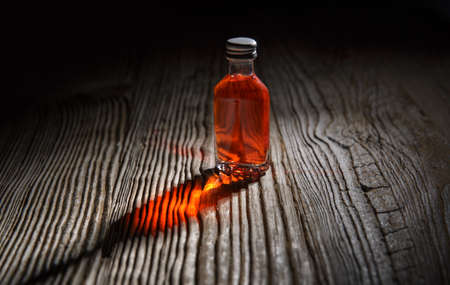 small bottle of red drink in the semi darkness on the wooden table. selective focusの写真素材