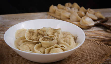 plate of homemade dumplings, and not boiled standing on the board. selective focus .の写真素材