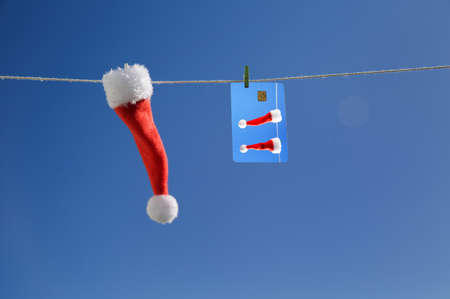 close-up little Santa Claus hat and a credit card with a picture hanging on a rope against the blue sky. close-up, merry Christmas celebration, advertising, bigboardの写真素材