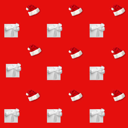 white gift boxes and Santa hat on red background. Seamless pattern, holiday concept .の写真素材