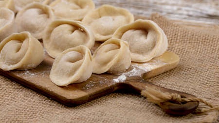 wooden food board with dumplings stands on burlap on the table. selective focusの写真素材