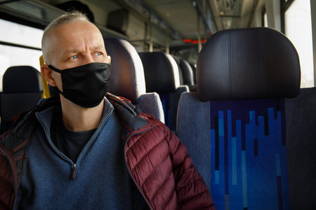 man rides train wearing black mask under sanitary restrictions next to an empty chair. selective...