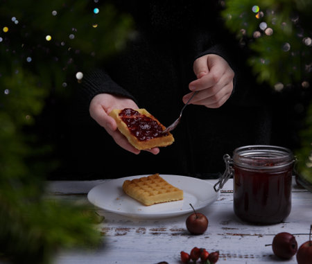 hand smear jam on waffles . Christmas tree. concept of Christmas. holiday and home comfort . High...