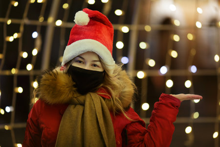 positive young girl in a black mask and Santa hat near the new year street illumination . selective focus .High quality photoの写真素材