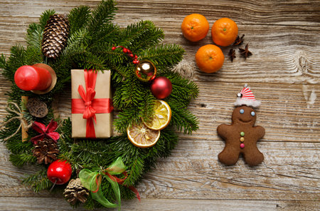 Christmas and holiday concept. gingerbread man lies on a wooden table. near a Christmas wreath and tangerines.の写真素材