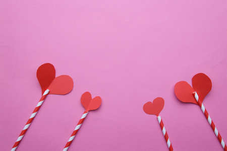 four striped tubes on the top of which are red paper hearts on a pink background. selective focus .High quality photoの写真素材