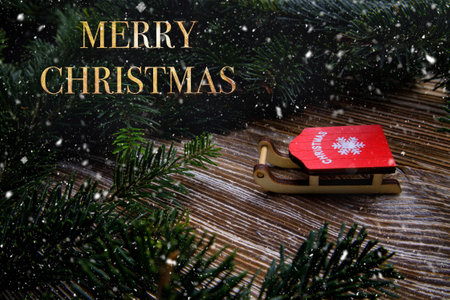 cute toy sleds are on wooden table and there are branches of Christmas tree nearby . selective focus .High quality photoの写真素材