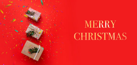 three boxes with gifts on a bright red background and the inscription Merry Christmas. selective focus .High quality photoの写真素材