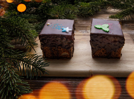 two gingerbread cookies in chocolate glaze on a wooden board. tree garland bokeh. Christmas holiday concept. selective focus.の写真素材