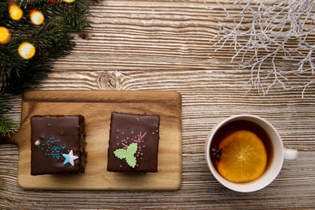 chocolate cakes and a cup of tea with orange and anise on a wooden table and branches of a Christmas tree bokeh. selective focus.High quality photo. High quality photoの写真素材