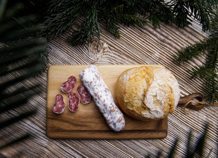 bread and sausage lie on a wooden board. surrounded by fir branches. concept of preparation for the holiday. High quality photoの写真素材