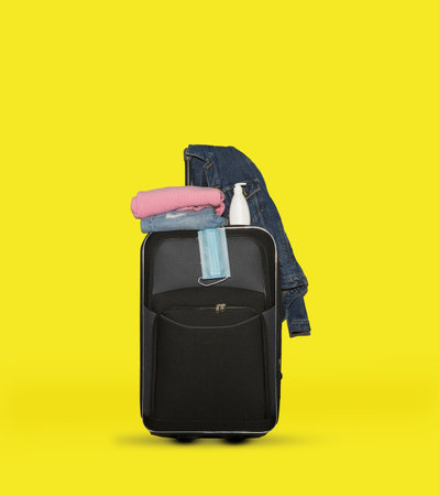 suitcase with a medical mask, a gel with a disinfectant and jeans and sweater. High quality photoの写真素材