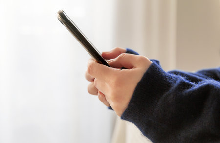 girl hands with a smartphone lie on the bed. selective focus. . High quality photoの写真素材