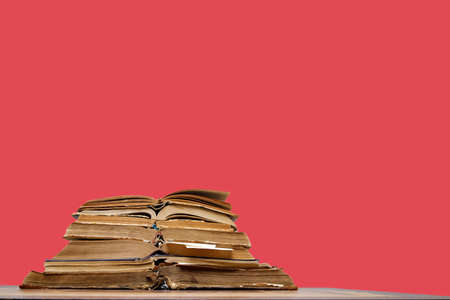there are many old open books with bookmarks on a wooden table, on a red background. High quality photoの写真素材