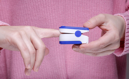 girl in a pink sweater holds a medical device on her finger. measuring the level of oxygen in the...