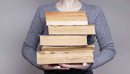 the hands of an invisible person holding many old books. learning and knowledge concept.High quality photoの写真素材