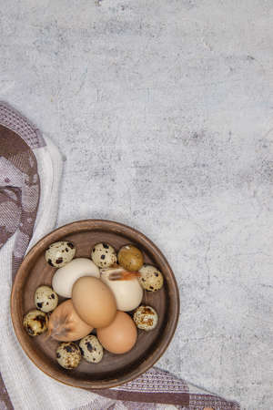 fresh quail and chicken eggs from the farm in a brown clay plate on a gray marble table. selective soft focus. top view .High quality photoの写真素材