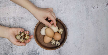 the girl hands folding chicken and quail eggs in a clay plate. selective focus .High quality photoの写真素材