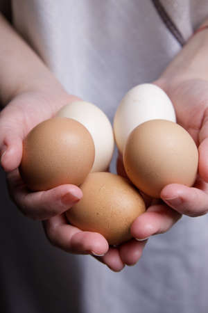 the hands of an invisible person are holding fresh chicken eggs from the farm in front of them in the palms of their palms.の写真素材