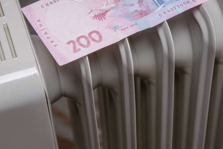 two hundred hryvnia bills lies on the heating radiator. The concept of high prices for electricity and heating. heating costs or property feesの写真素材