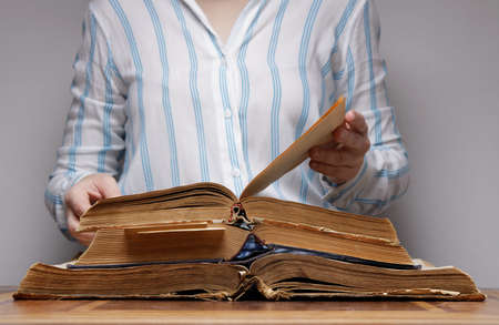 girl leafing through old books that lie on the table. selective focus. High quality photoの写真素材