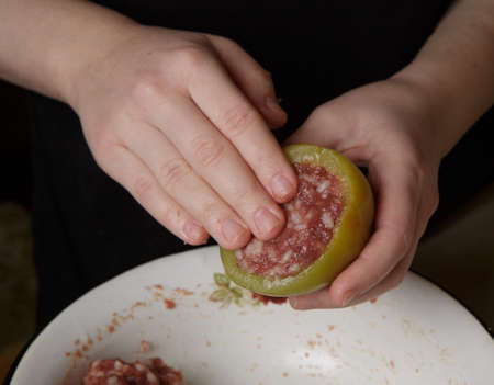 hands of girl who prepares stuffed paprika, filling vegetable with minced meat. selective focus.High quality photoの写真素材