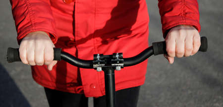 Hands of teenager dressed in red winter jacket on the steering wheel of scooter. selective focus. High quality photoの写真素材