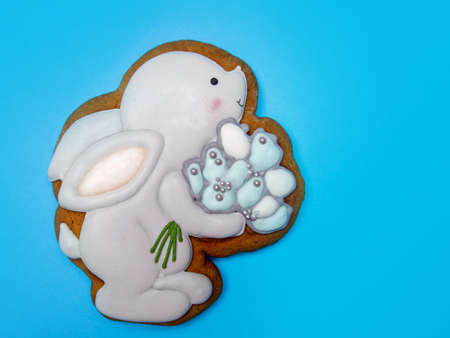 gingerbread in the shape of an Easter bunny that holds a bouquet of flowers on the blue background . High quality photoの写真素材