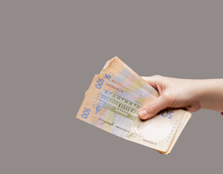 the girl hand holds bills of large denomination of the Ukrainian bank on a grey background. selective focus . High quality photoの写真素材