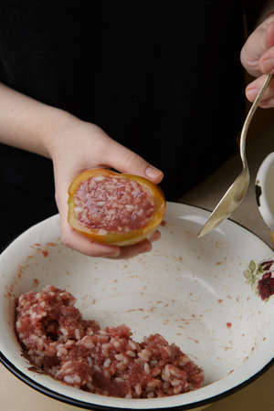 Hands fill sweet green peppers with minced meat and rice. Step-by-step recipe for homemade stuffed bell peppers.selective soft focusの写真素材