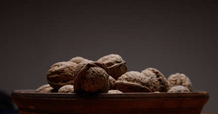 dark photo. walnuts on brown clay plate against dark background. selective focus. background blur....