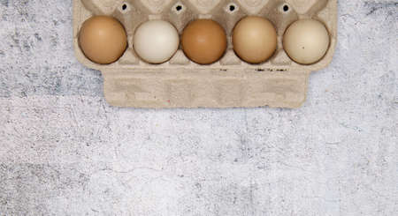 Cardboard tray for eggs top view .Brown and white chicken eggs in a paper box on gray background ....