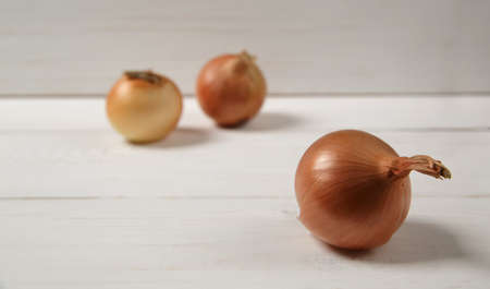 Fresh ripe onions on a white wooden table. Blurred background. Selective focus. High quality photoの写真素材
