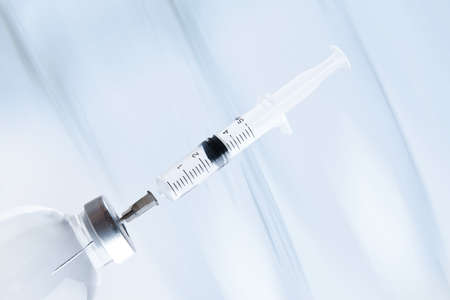 medicine bottle with a syringe stuck into the cap. on a light background. selective focus.