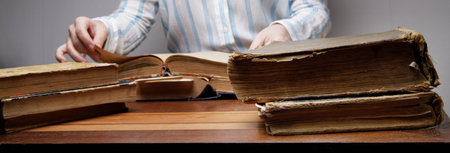 the hands of an invisible person leaf through the pages of an old book lying on a wooden table in a university or school library.vintage paper texture. selective focusの写真素材