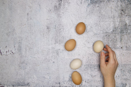 hand puts chicken eggs of different color on a concrete table. selective focus.High quality photoの写真素材