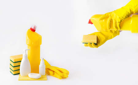 hands in latex gloves hold a sponge and a bottle of disinfectant, and there are bottles of detergent...