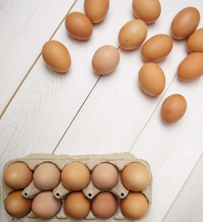 cassette filled with fresh chicken eggs and next to several eggs on wooden white table. selective focus.top viewの写真素材