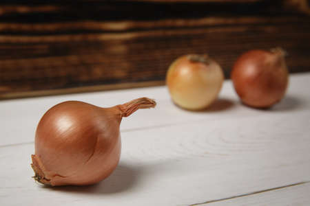 Fresh ripe onions on a white wooden table. Blurred background. Selective focus. High quality photoの写真素材