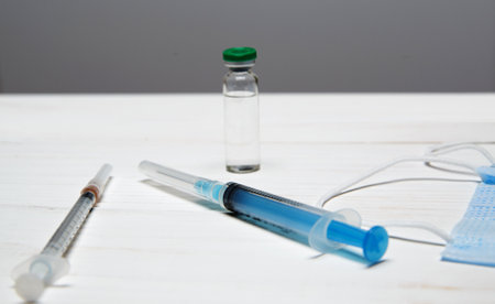 two syringes for injections and bottle with a vaccine lie on light wooden table. selective focus.High quality photoの写真素材