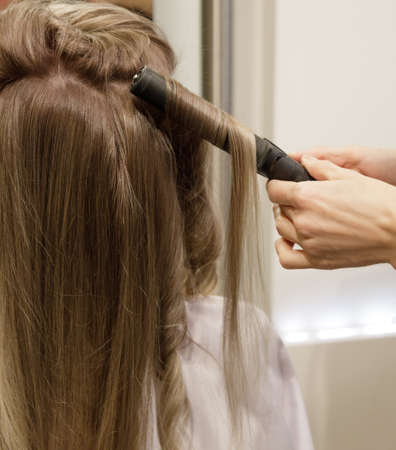 Invisible hairdressers hands make a customer hair perm. selective focus.High quality photoの写真素材