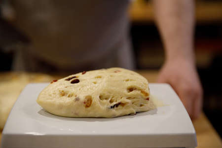 A piece of dough with raisins rests on the culinary scales for measuring the portion. selective focus.High quality photoの写真素材