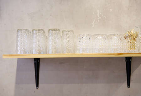 row of clean glass glasses stands on a shelf against the wall. selective focus. High quality photoの写真素材