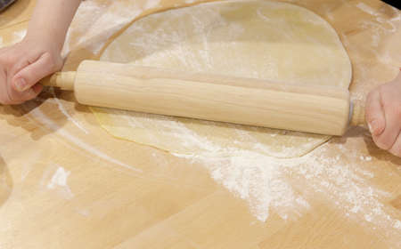 the hands of the cook roll out the thin dough. concept of making pizza or baking. selective focusの写真素材